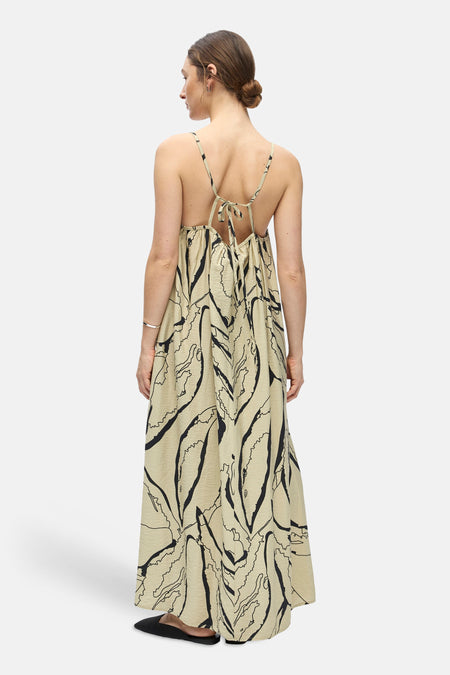 Een beige mouwloos kleedje van OBJECT met zwarte abstracte print, kreukeltextuur, open rug en strikbandjes, van achteren gezien.