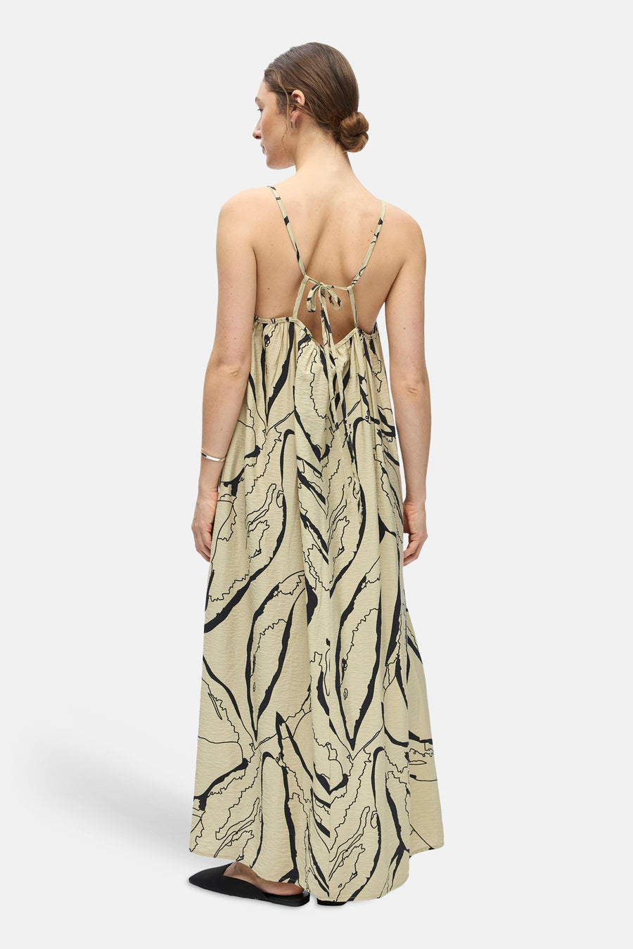 Een beige mouwloos kleedje van OBJECT met zwarte abstracte print, kreukeltextuur, open rug en strikbandjes, van achteren gezien.