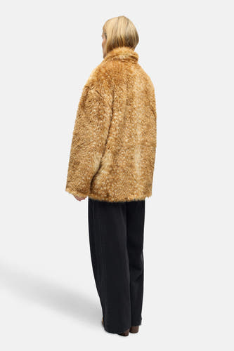 Bruine korte jas van OBJECT, met een faux fur textuur en gedragen met een zwarte broek.
