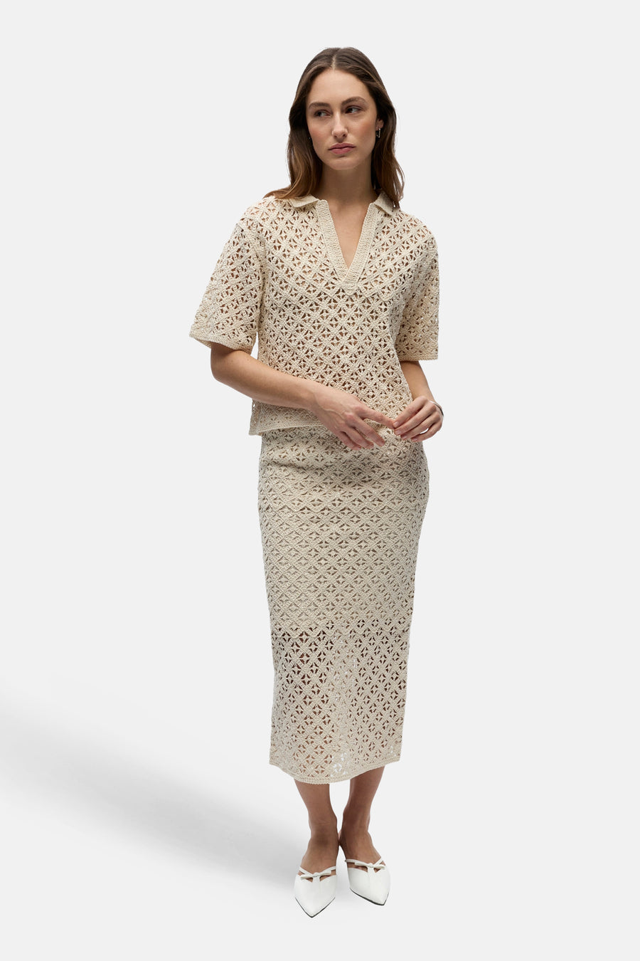 Pull de couleur écru à col en V de OBJECT, avec motif ajouré ouvert, porté avec une jupe assortie et des mules blanches pointues.