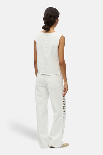 Witte blouse met korte mouwen van OBJECT, van achteren gezien met een naad, bijpassende jeans met opengewerkte details en lichte schoenen.