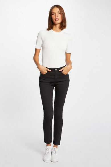 Pantalon noir à 5 poches de Morgan De Toi, coupe ajustée, modèle avec pull blanc et baskets, vue de face