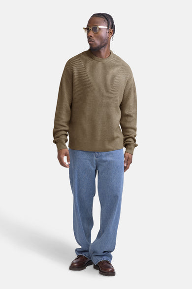 Beige trui met ronde hals van REDEFINED REBEL, geribd breisel, gedragen met een losse jeans en bruine schoenen.
