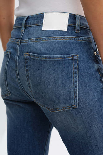 Donkerblauwe denim slim jeans van OPUS, met achterzak en witte patch op de tailleband, rug aanzicht.
