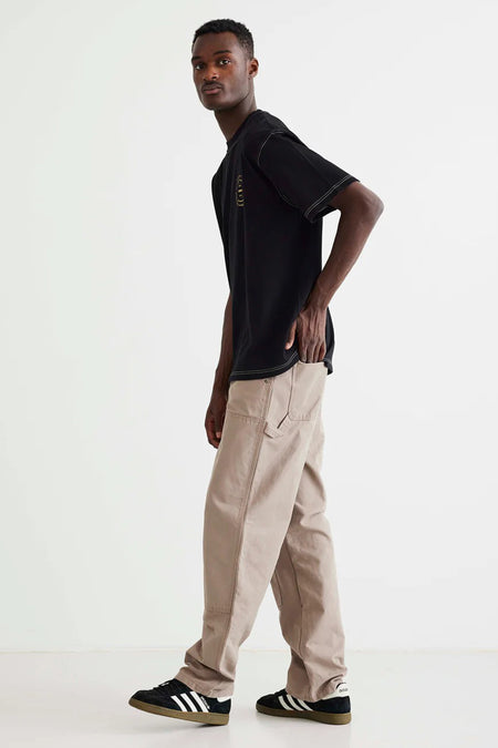 Zwart T-shirt van WOODBIRD, met korte mouwen en contrasterende stiksels, gedragen met kaki broek en zwarte sportschoenen.