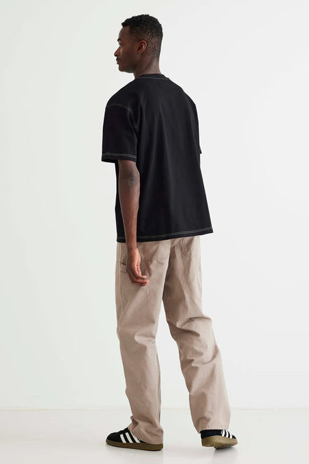 Zwart T-shirt van WOODBIRD, met korte mouwen en contrasterende stiksels, gedragen met beige broek en zwarte sneakers.