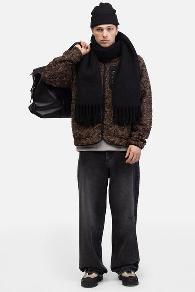 Donkergrijze wijde jeans van REDEFINED REBEL, gedragen met een bruin teddy jack, zwarte muts en sjaal.
