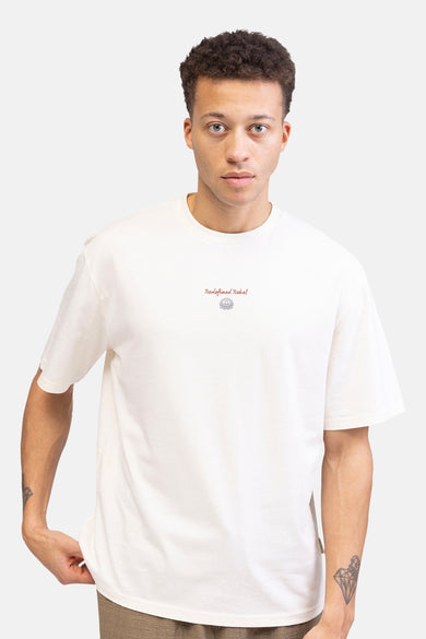 Ecru T-shirt met korte mouwen van REDEFINED REBEL, met kleine logo-opdruk en model met tattoo op de arm.
