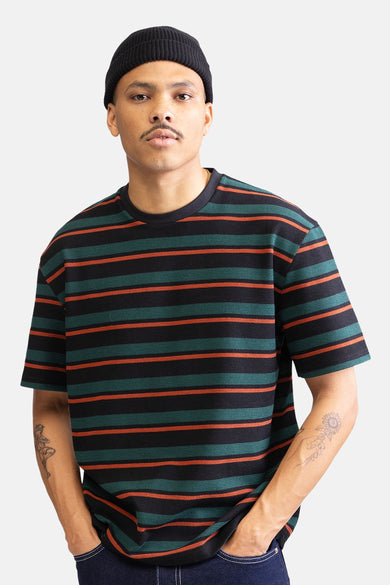 T-shirt à manches courtes multicolore de REDEFINED REBEL, rayé de noir, vert et orange, porté avec un chapeau noir.