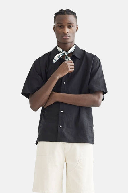 Chemise noire à manches courtes de WOODBIRD, avec des boutons blancs et un bandana dénoué.