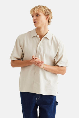 Chemise beige à manches courtes de WOODBIRD, avec col boutonné et portée avec un pantalon foncé.