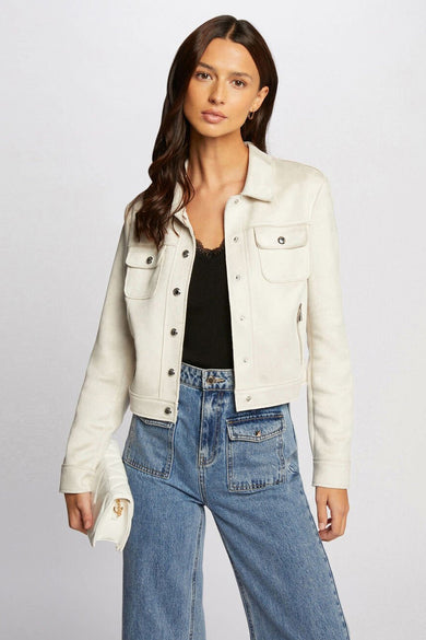 Beige korte jas van Morgan De Toi, met klepzakken en knoopsluiting, gecombineerd met een zwarte top en blauwe jeans.
