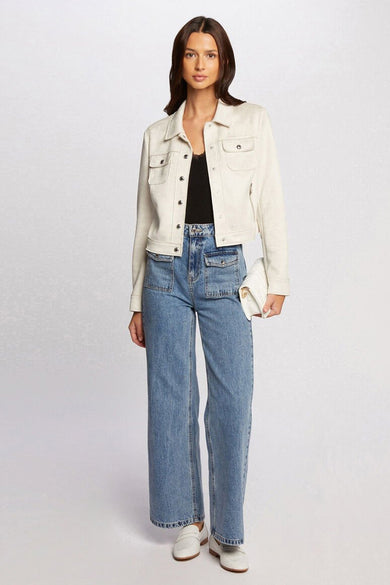 Beige korte jas van Morgan De Toi, gedragen met een zwarte top, blauwe jeans met zakken en witte loafers.
