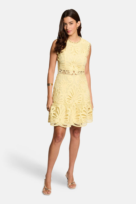 Robe courte sans manches en dentelle jaune de Morgan De Toi avec taille ajourée et bas à volants, portée avec des bijoux dorés.