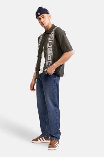 Groen gebreid hemd met korte mouwen van REDEFINED REBEL, met wit en bruin geometrisch patroon. Gedragen over een wit T-shirt.