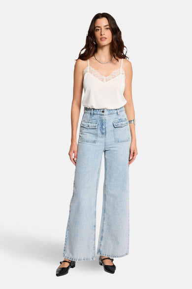 Witte top met spaghettibandjes van Morgan De Toi, afgewerkt met kanten details rondom de halslijn, gecombineerd met wijde jeans.