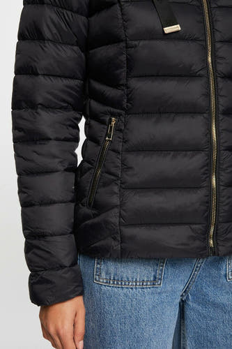 Manteau court noir de Morgan de Toi avec des fermetures éclair dorées et un détail de poche, porté avec un jean bleu.