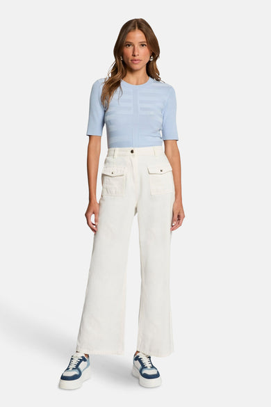 T-shirt bleu avec col rond de Morgan De Toi, avec des lignes horizontales et porté avec un pantalon blanc.