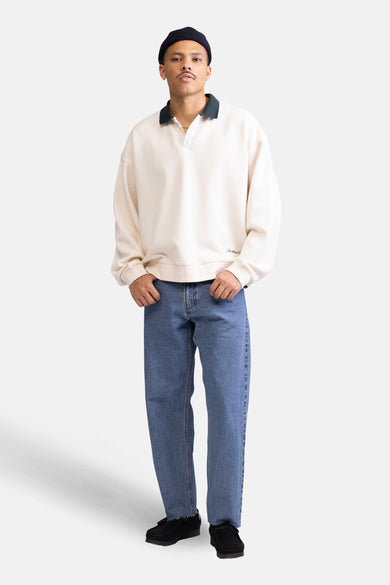 Ecru sweater van REDEFINED REBEL, met een donkergroene kraag en gedragen met blauwe jeans en zwarte schoenen.
