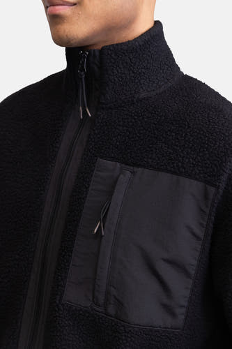 Fleece noir de REDEFINED REBEL avec col montant, fermeture éclair et poche poitrine.