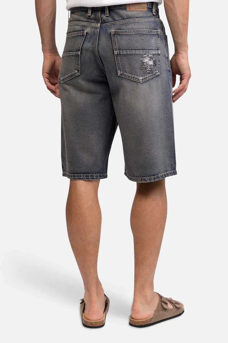 Blauwe mid-lengte jeansshort van REDEFINED REBEL, achterzijde met verweerd denim, patch op achterzak, model in sandalen