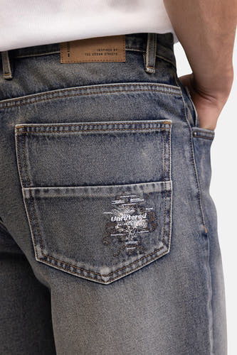 Blauwe denim jeansshorts van REDEFINED REBEL, achterzijde met geborduurd logo en verweerd look, close-up.