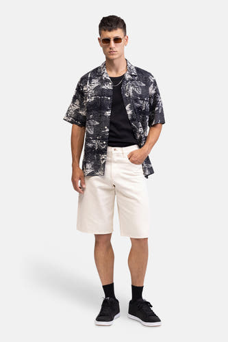 Ecru jeansshort van REDEFINED REBEL, gedragen door een man met een zwart-wit geprint overhemd en zwarte sneakers.