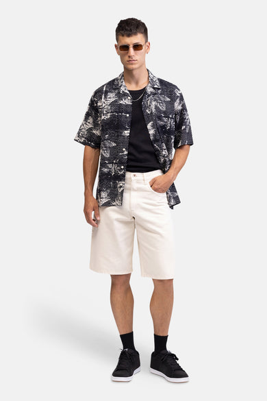 Ecru jeansshort van REDEFINED REBEL, gedragen door een man met een zwart-wit geprint overhemd en zwarte sneakers.