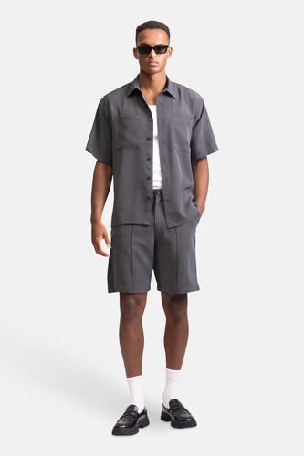 Grijze short van REDEFINED REBEL, gecombineerd met een grijs overhemd, witte sokken en zwarte loafers.