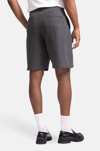 Grijze short van REDEFINED REBEL, met achterzakken, gecombineerd met witte sokken en zwarte instappers.