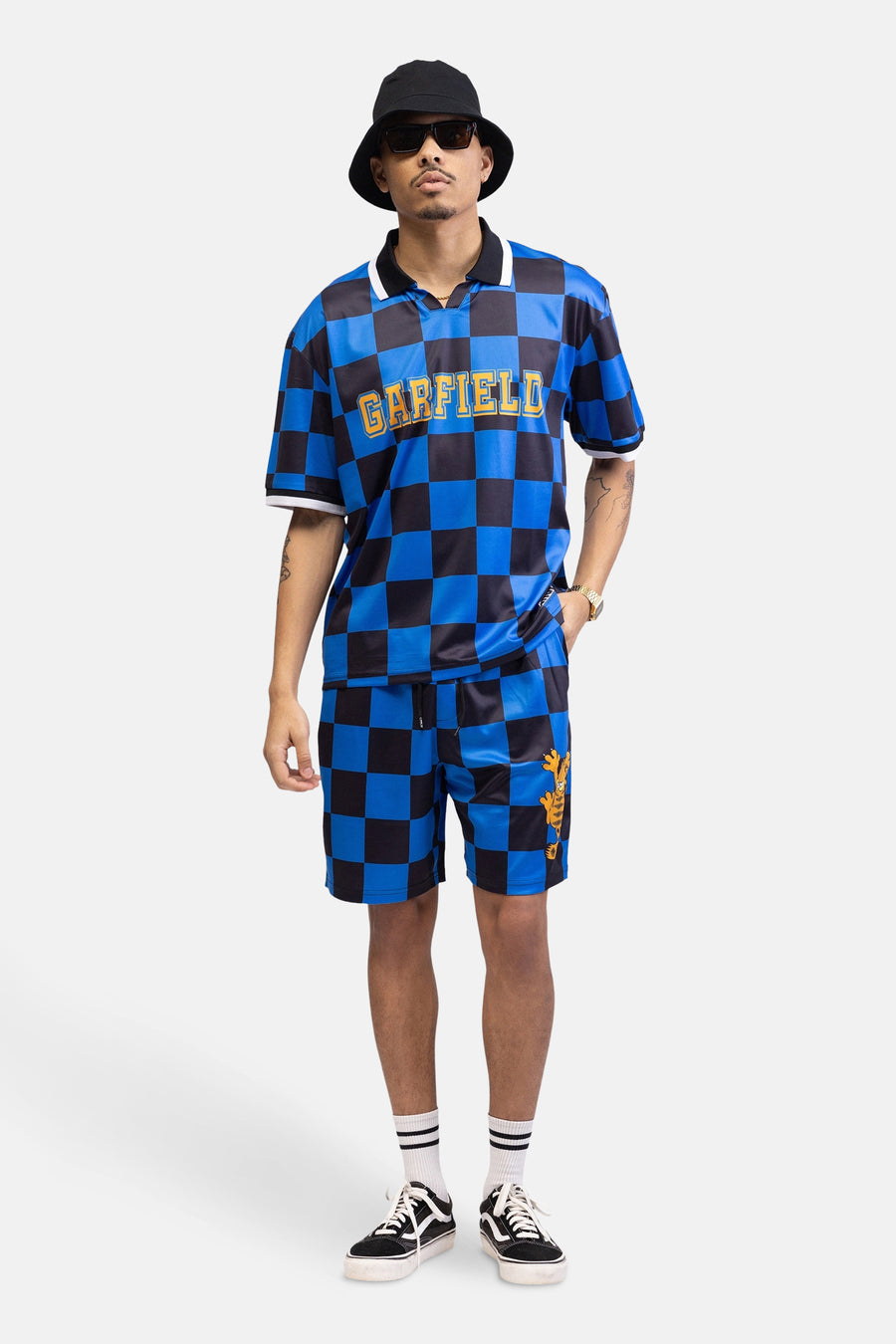 Man in een blauw-zwart geblokt Garfield-pak met zwarte hoed en zonnebril.