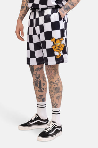 Persoon met getatoeëerde benen, draagt geruite Garfield-short, witte sokken met strepen en zwarte Vans.
