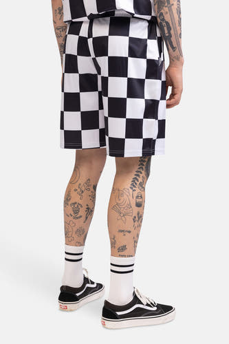 Zwarte en witte shorts met dambordpatroon van CULT, met sokken met strepen en zwarte schoenen.