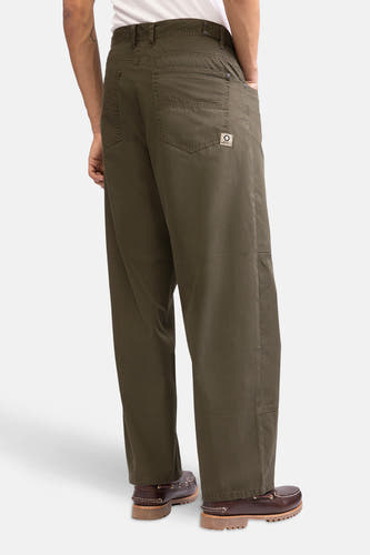 Groene broek van REDEFINED REBEL, met achterzakken, gedragen met bruine schoenen.
