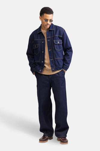 Donkerblauwe denim jeans wide van REDEFINED REBEL, met een losse pasvorm, gecombineerd met een bruine trui en bruine schoenen.