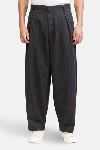 Grijze broek van REDEFINED REBEL, met krijtstrepen en wijde pijpen, gedragen met witte sneakers.
