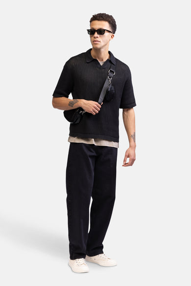 Wijde zwarte jeans van REDEFINED REBEL, met een losse pasvorm en gecombineerd met een zwart gebreid shirt en crèmekleurige sneakers.