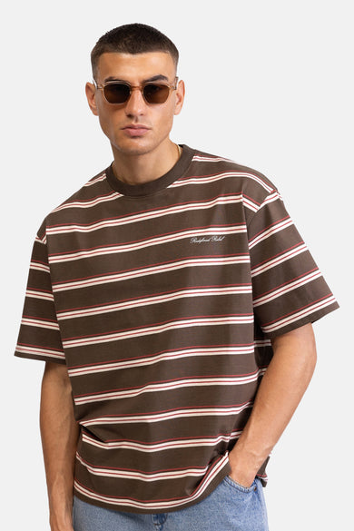 T-shirt multicolore de REDEFINED REBEL, avec des rayures horizontales marron, blanc et rouge, porté par un homme avec des lunettes de soleil.