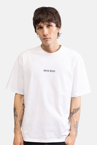 Wit T-shirt van REDEFINED REBEL met 'HOUSE RULES' op de borst, gedragen door een man met zichtbare tatoeages.