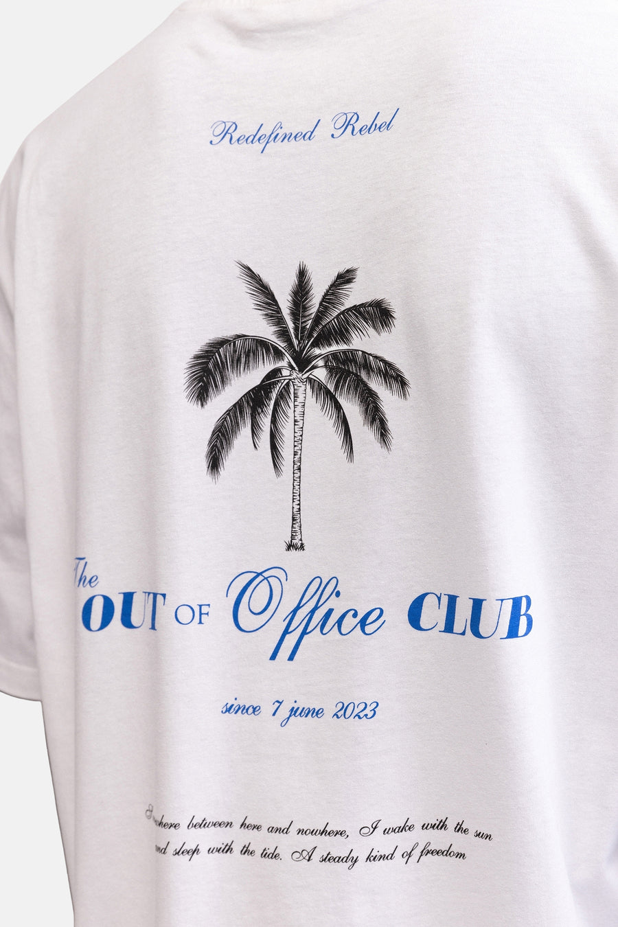 Wit T-shirt van REDEFINED REBEL met blauwe 'Redefined Rebel' tekst, een palmboom en 'OUT of Office CLUB' op de rug.