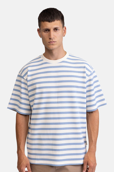 Gestreepte T-shirt in wafelstof van REDEFINED REBEL met witte en lichtblauwe horizontale strepen, korte mouwen en ronde hals, gedragen door een man.