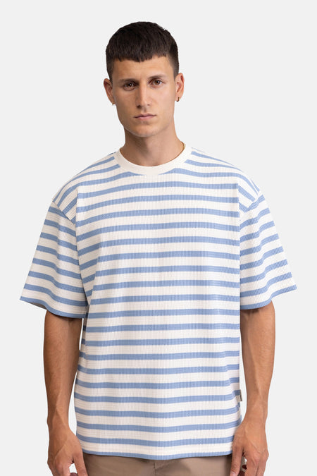 Gestreepte T-shirt in wafelstof van REDEFINED REBEL met witte en lichtblauwe horizontale strepen, korte mouwen en ronde hals, gedragen door een man.