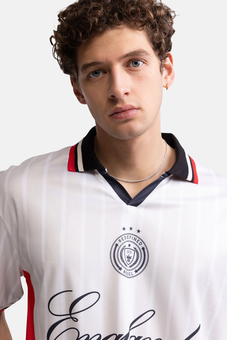 Multicolor polo met witte basis en rode accenten van REDEFINED REBEL, met logo en scriptprint, close-up van model