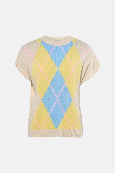 Gilet sans manches beige de Terra di Siena, avec un motif losange argyle bleu et jaune, porté sur un jean à jambes larges et des escarpins marron.