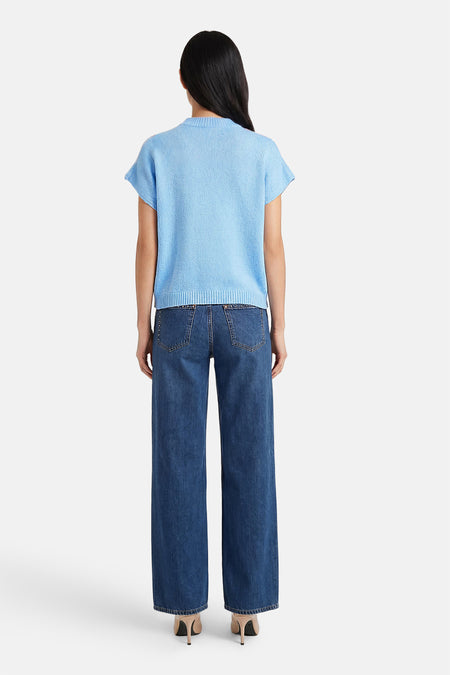 Gilet court sans manches bleu de Terra di Siena, avec une texture finement tricotée et combiné avec un jean ample et des talons.
