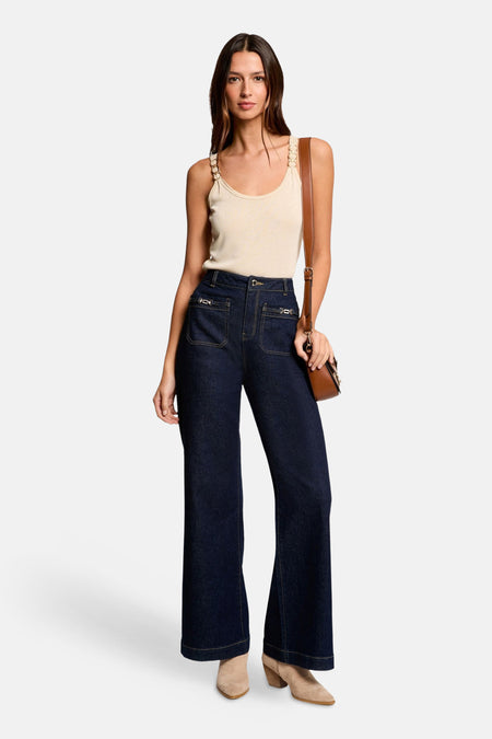 Beige tanktop van Morgan De Toi, met decoratieve schouderbandjes, gecombineerd met donkere jeans met hoge taille en bruine tas.
