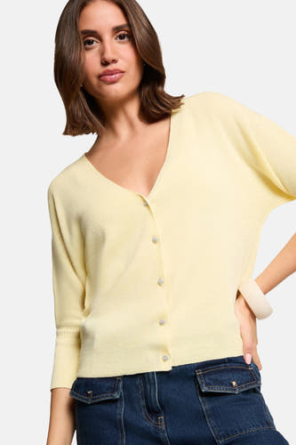 Gele cardigan van Morgan De Toi met knoopsluiting, driekwart mouwen en donkere jeans met zakken.
