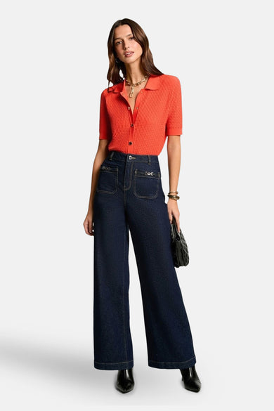 Maillot orange de Morgan De Toi, à manches courtes, porté avec des jeans bleus foncés larges et des bottines noires.
