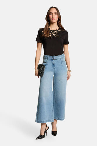 Lichtblauwe denim jeans wide van Morgan De Toi, met riem, gecombineerd met een zwarte top en zwarte hakken.