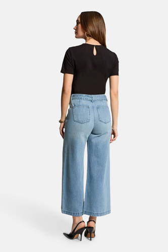 Lichtblauwe wide jeans van Morgan De Toi, met achterkant en zwarte hakken.
